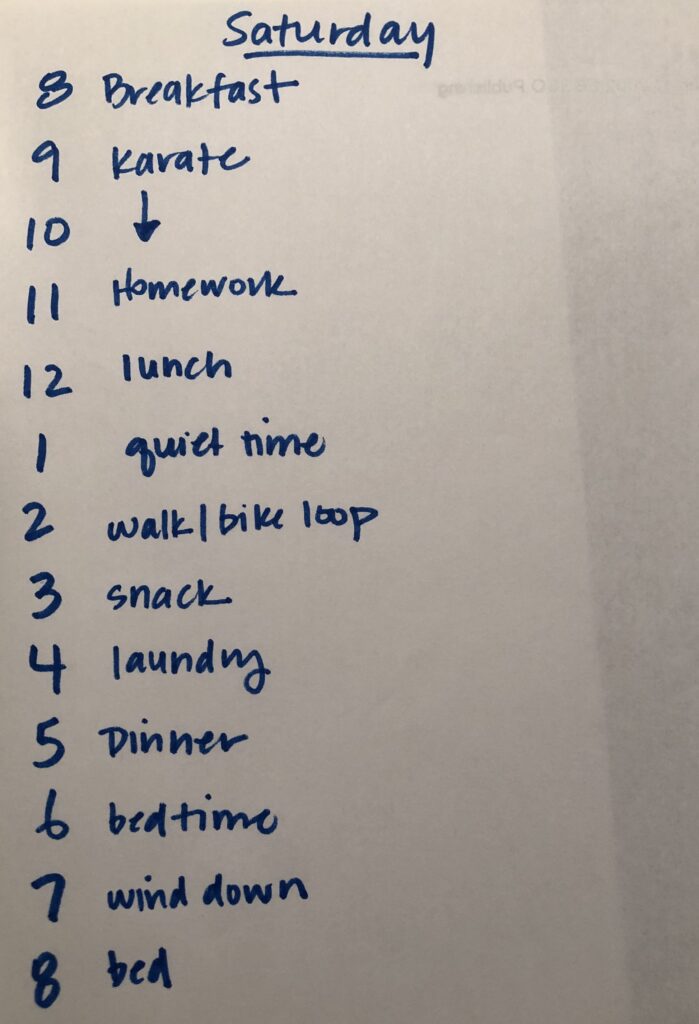Image of handwritten Saturday Schedule.  Text reads: 8 Breakfast, 9 Karate, 10 (down arrow), 11 homework, 12 lunch, 1 quiet time, 2 walk/bike loop, 3 snack, 4 laundry, 5 dinner, 6 bedtime, 7 wind down, 8 bed